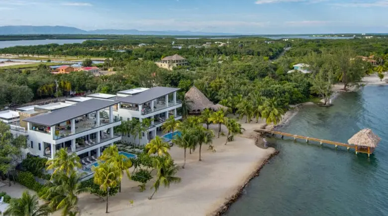 Aerial view of the luxury swimming pool surrounded by tropical palm trees and modern vacation villas at The Villas at Playa de Coco in Belize.
