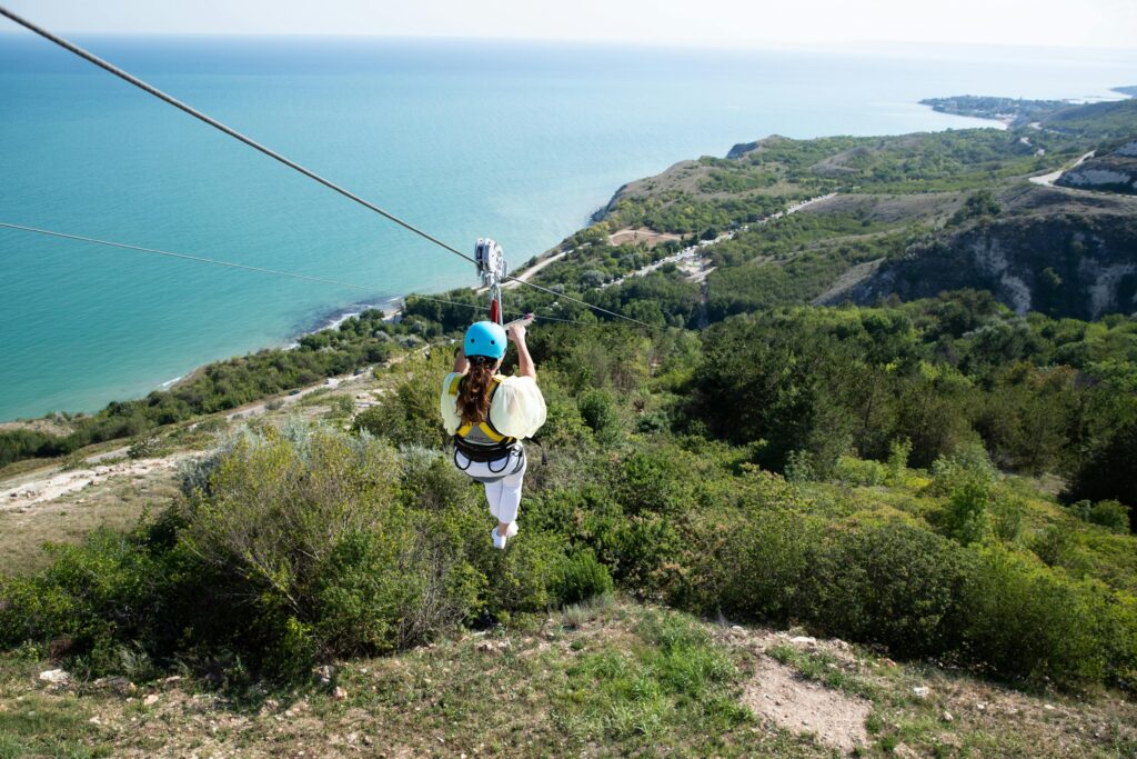 Person zip-lining over a lush tropical forest with panoramic views of the turquoise ocean and Belize coastline
